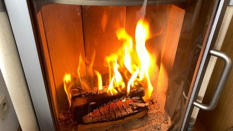 Ein Holzofen-Kamin, in dem wenige Holzscheite brennen.