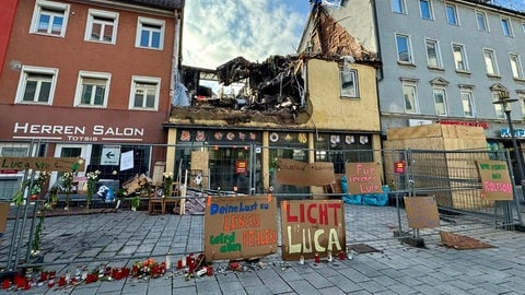 Zum Gedenken an den getöteten Luca S. stehen Kerzen vor dem zerstörten Mietshaus.