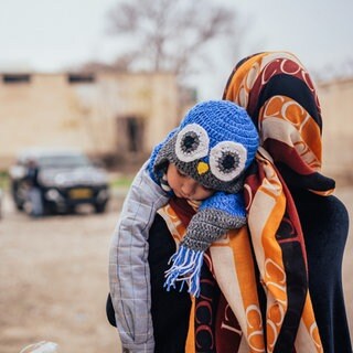 Eine afghanische Frau trägt ihren schlafenden Jungen. 