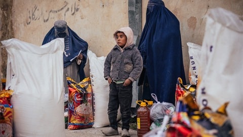 Ein afghanischer Junge steht zwischen zwei vollverschleierten Frauen. 