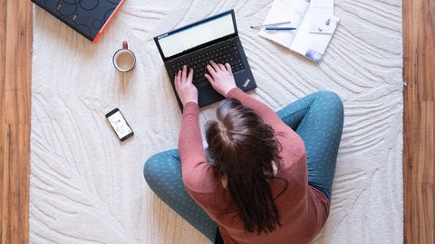 Junge Frau an einem Laptop: Mitglieder der "Gen Z" wünschen sich Studien zufolge häufig Arbeitserleichterungen wie die Möglichkeit zum Homeoffice.