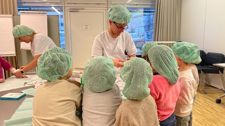 Ein Arzt erklärt mehreren Erstklässern aus einer Grundschule in Stuttgart-Botnang, was bei einer Verbrennung oder Verbrühung zu tun ist. 