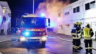 Ein Feuerwehrauto steht vor den Wohncontainern eines Flüchtlingsheims