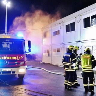 Ein Feuerwehrauto steht vor den Wohncontainern eines Flüchtlingsheims