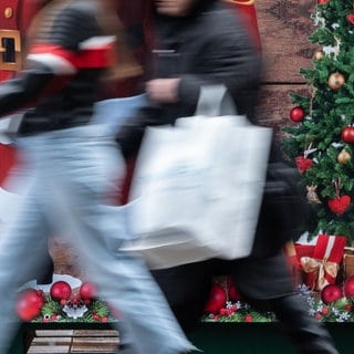 Passanten gehen an einem weihnachtlich geschmückten Verkaufsstand auf der Königstraße in Stuttgart vorbei. (Archivbild)