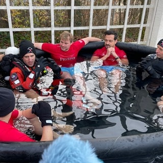 Mehrere Menschen sitzen bekleidet in einer großen Tonne mit Eiswasser, darunter Ex-VfB-Profi Timo Hildebrand.