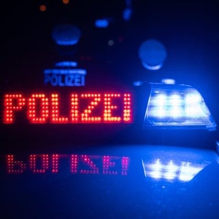 In Weissach im Tal endet ein Streit tödlich. Polizisten stehen an einem Auto mit Polizei-Leuchtschrift und Blaulicht. (Symbolbild)