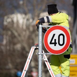 Ein Mitarbeiter der Stadt montiert ein Tempo 40 Schild. (Symbolbild)