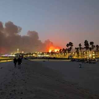 An einem Strand in Marina del Rey im County Los Angeles ist im Hintergrund das Feuer der Waldbrände zu sehen. Bei den Bränden im US-Bundesstaat Kalifornien, sind mehrere Menschen ums Leben gekommen.