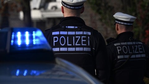 Ein Streifenwagen mit Blaulicht und Beamte der Polizei in Uniform:  Ermittler untersuchen das Tötungsdelikt an einer jungen Frau in Stuttgart. (Symbolbild)