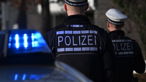 Zwei Polizisten stehen hinter einem Streifenwagen. In Korntal-Münchingen im Kreis Ludwigsburg sollen Unbekannte einen Zehnjährigen in einen teilweise zugefrorenen See. Laut Polizei sind die mutmaßlichen Täter ebenfalls minderjährig. (Symbolbild)