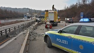 Ein Polizei- und ein Feuerwehrfahrzeug stehen auf der A81 vor dem Engelbergtunnel. Zwischen einer Betonabsperrung und der Leitplanke, steht ein zerstörtes Fahrzeug.