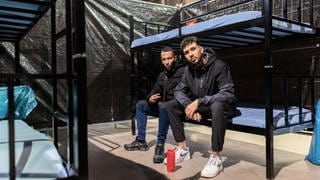 Zwei Männer aus Algerien sitzen in einer neuen Notunterkunft in Offenburg auf ihrem Stockbett. 