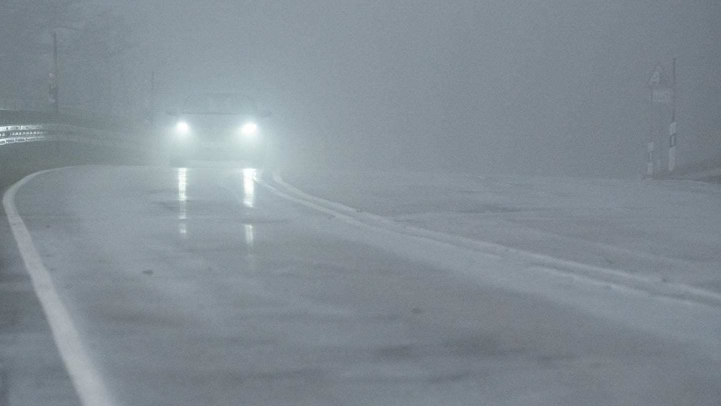 Ein Auto fährt während eines Sturmtiefs auf der Bundesstraße 317 am Feldberg im Nebel.