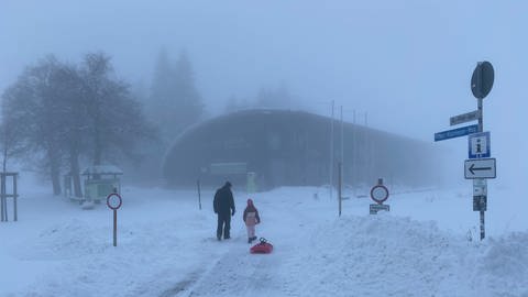 Mann mit Kind und Schlitten geht durch Winterlandschaft