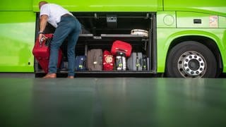 ein Mann räumt Gepäckstücke in einen grünen Bus