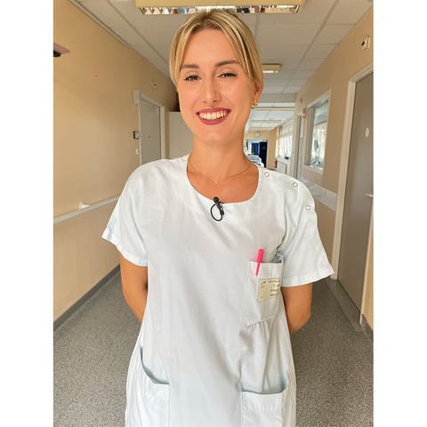 Eine junge Krankenschwester lächelt in die Kamera.