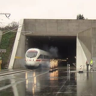 Ein ICE und ein Güterzug durchfahren mit Feuerwerk den Katzenbergtunnel bei der Eröffnung 2012
