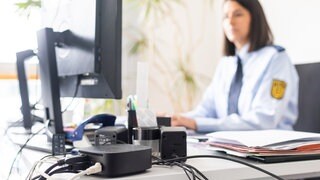 Eine Frau in Polizeiuniform sitzt an einem Computer.