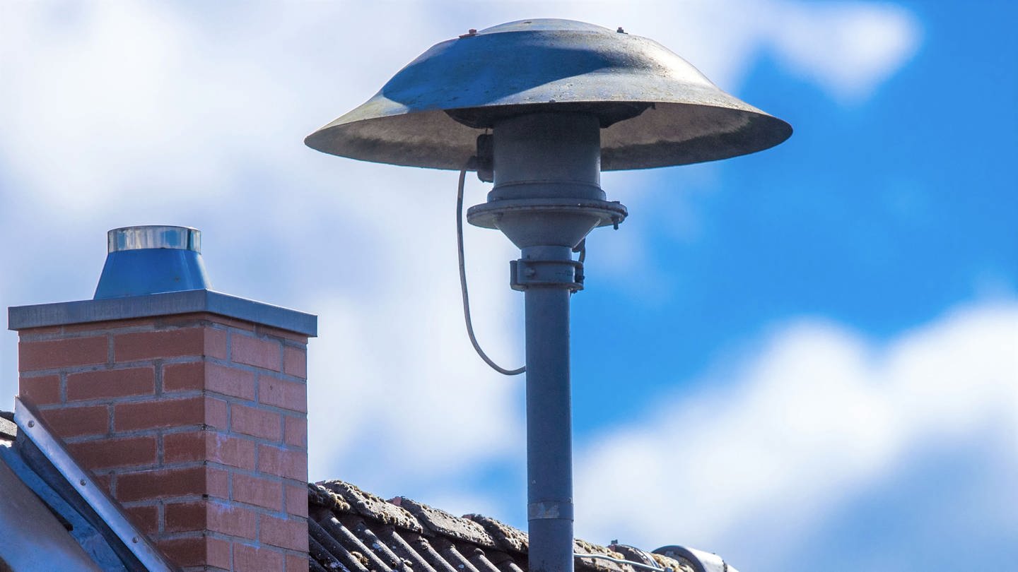 Eine Alarmsirene steht auf einem Hausdach.