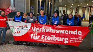 Bei der Infoveranstaltung gab es auch Gegner des Stadttunnels. Sie tragen blaue Oberteile mit einem durchgestrichenen Autobahnsymbol und halten ein Transparent. "Verkehrswende für Freiburg", fordern die neun Personen vom Radentscheid.