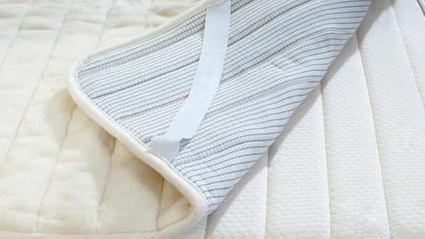 Eine Matratze mit einem weiß-grauen Schoner (Symbolbild)