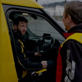 Koordinator Heiko Jordan erklärt Paketzusteller Joachim Schnurr ein neues Postauto