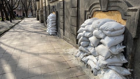 Sandsäcke sind vor den Kellerfenstern eines alten Gebäudes gestapelt.