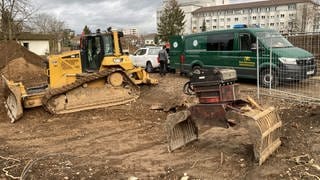 Eine Baustelle mit Fahrzeugen, darunter ein grünes vom Kampfmittelbeseitigungsdienst.