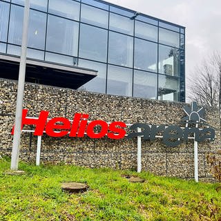 Vor einer Steinwand pragt groß das Logo der Helios-Arena, die große Eishalle in Villingen-Schwenningen, in der Spiele der Wild Wings stattfinden. 