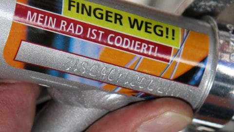 Ein Aufkleber an einem Rad mit der Aufschrift "Finger weg! Mein Rad ist codiert" um einen eingravierten Code im Fahrradrahmen.