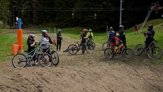 Fahrradfahrer stehen vor einem Skilift 