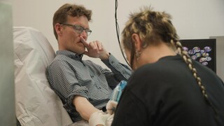 Ein junger Mann bekommt ein Organspende-Tattoo und verzieht leicht das Gesicht.