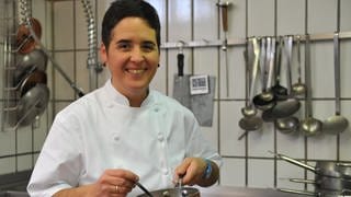 Douce Steiner steht in ihrer Kochjacke in der Küche mit einem Topf in der Hand. Der Restaurantführer "Gault&Millau" hat sie als "Köchin des Jahres" ausgezeichnet.
