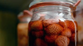 Nahaufnahme von dunkelroten, eingekochten Erdbeeren in einem Weck-Glas.