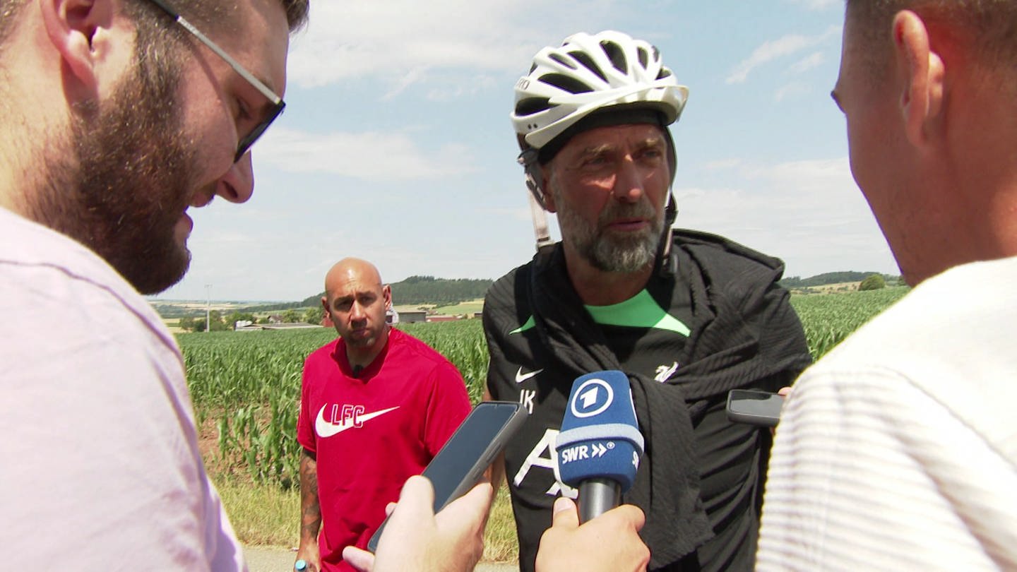 zwei Reporter und ein Mann mit Fahrradhelm