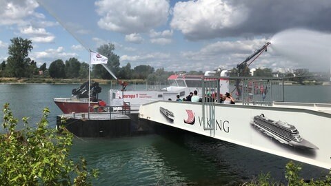 Ein langes weißes Boot liegt am Rhein vor Anker - es ist ein Löschschiff, dass Brände vom Wasser aus löschen kann. 