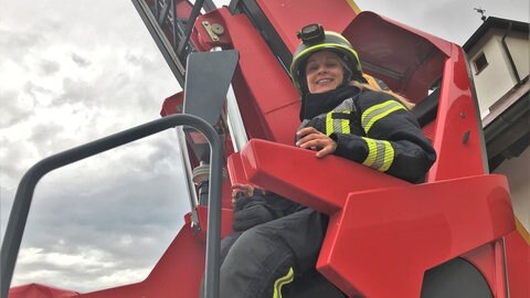 Feuerwehrfrau Jessica Kolb sitzt in einem Feuerwehrkran.