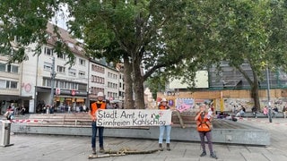 Aktivisten halten Schilder hoch, um auf die anstehenden Rodungen im Dietenbachwald hinzuweisen