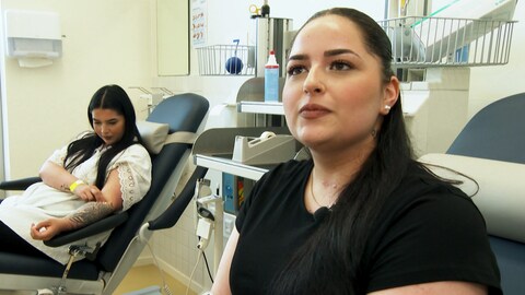 Zwei junge Frauen mit Schwarzen Haaren spenden Blut in der Blutspendezentrale.