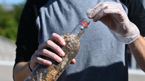 Ein Kippen-Sammler mit einer Flasche voller Zigarettenstummel