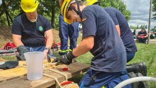 Jugendliche in THW-Uniform binden Holzlatten aneinander.