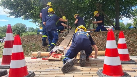 Jugendliche in THW-Uniform binden Holzlatten aneinander.