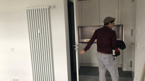 Ein Mann geht aus der Tür, ein Teil der Küche ist zu sehen