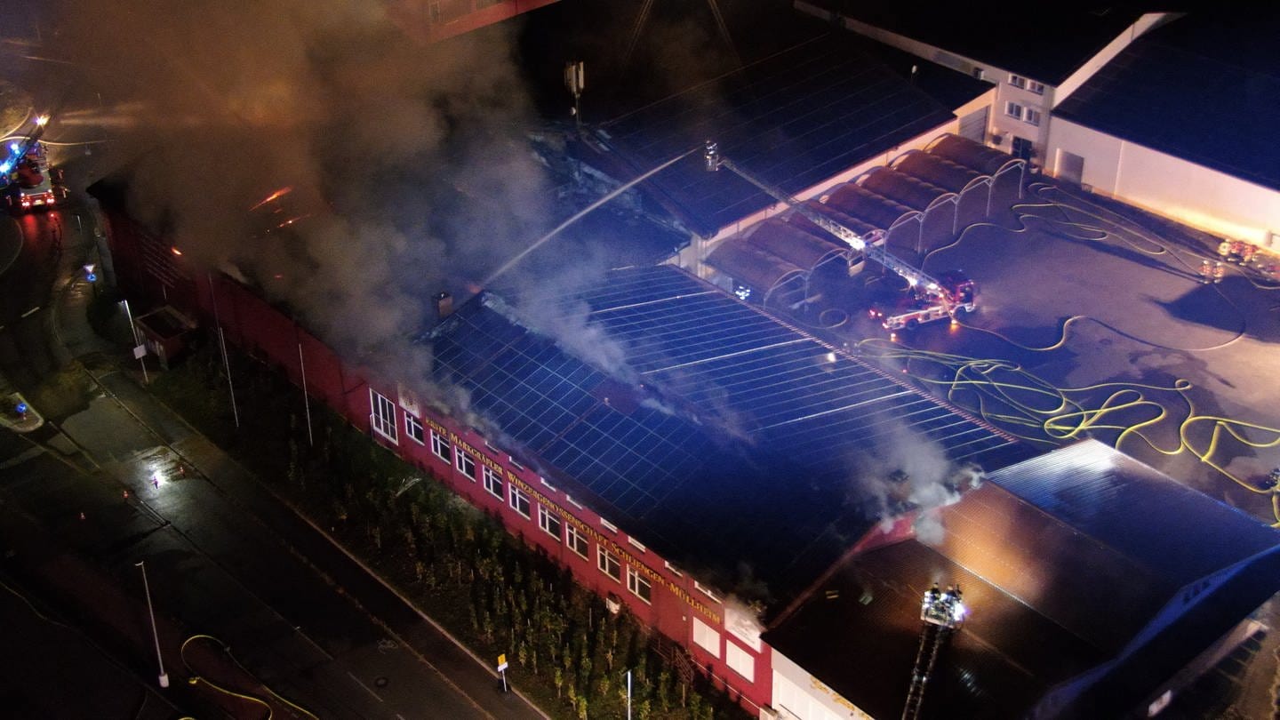 Blick aus der Luft auf den Brandort: Das Dach eines Gebäudes der Winzergenossenschaft steht in Flammen.