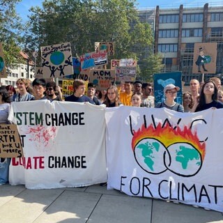 Schülerinnen und Schüler demonstrieren mit Plakaten für Klimaschutz.