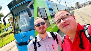 Zwei Männer vor einer Straßenbahn in Freiburg.