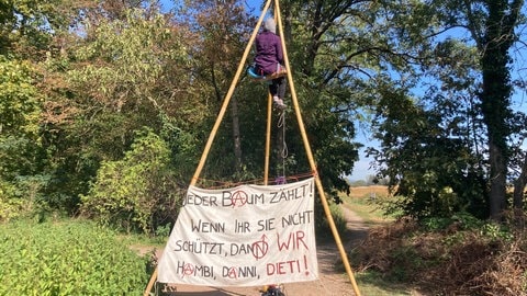 Aus drei langen Holzstangen haben die Aktivisten im Freiburger Dietenbachwald eine Art Tippi gebaut. Eine Aktivistin hängt in dem Gestänge, darunter hängt ein Banner mit der Aufschrift: "Jeder Baum zählt."