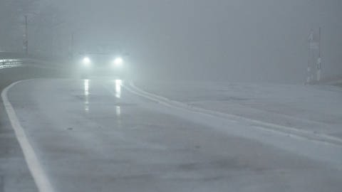 Ein Auto fährt während eines Sturmtiefs auf der Bundesstraße 317 am Feldberg im Nebel. 