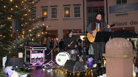 Zwei Musiker stehen auf einer weihnachtlich dekorierten Bühne.